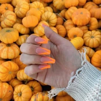Orange autumn manicure photographed with pumpkins