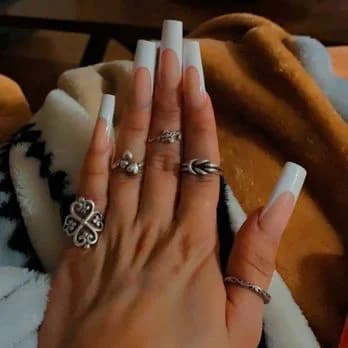 Long white coffin nails styled with decorative rings